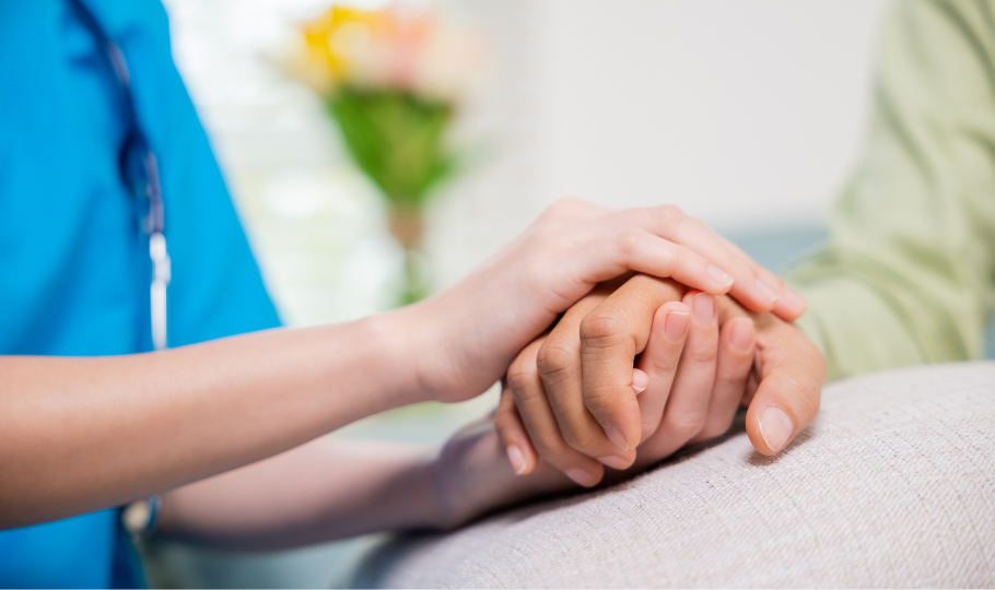 la mano di un'infermiera tiene dolcemente la mano di una persona in cura